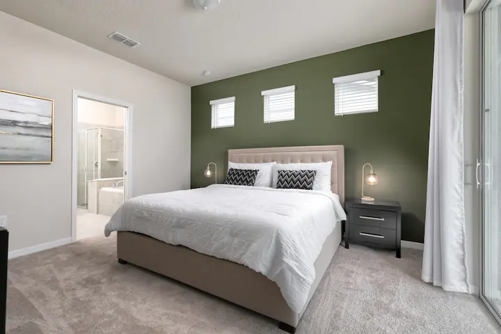 Modern king suite with calming green accent wall and private ensuite bath.