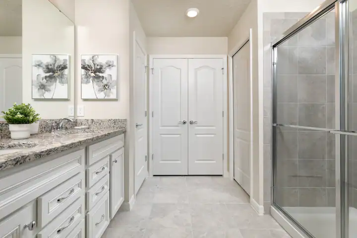 Spacious bathroom with granite double vanity, walk-in shower, and elegant tile floors.