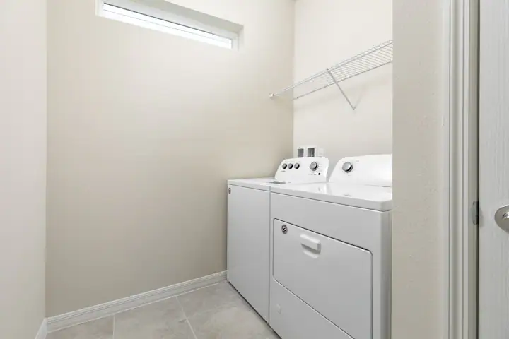 Convenient in-home laundry room with washer, dryer, and plenty of overhead storage.