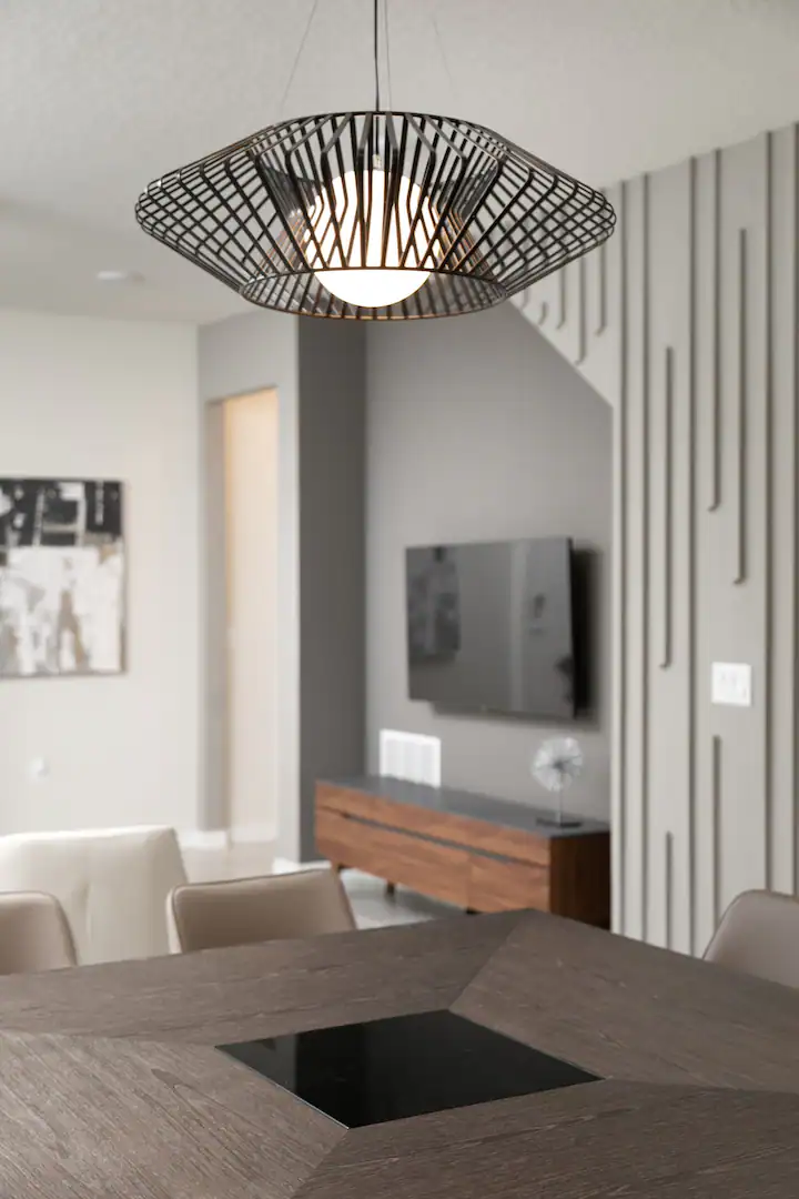 Modern pendant light over a sleek wood dining table adds style to the open layout.