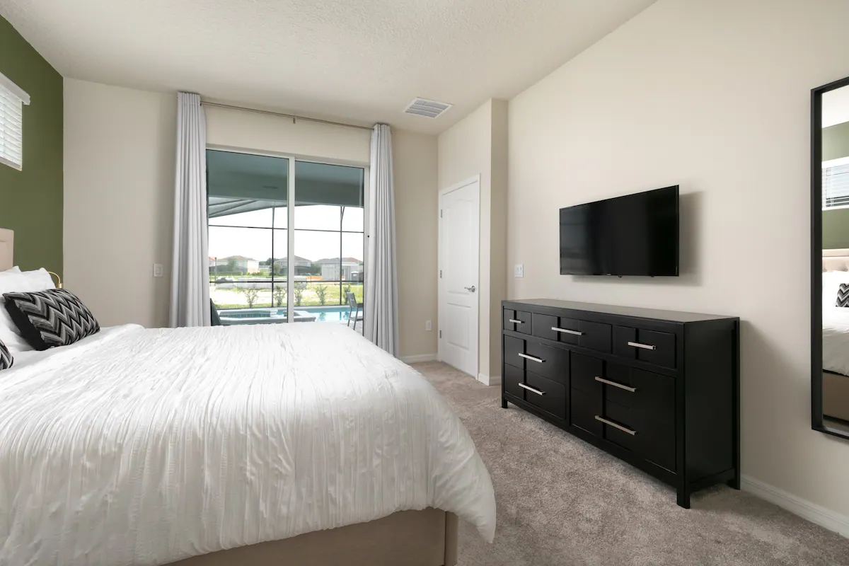 Spacious king suite with pool views, flat-screen TV, and modern black dresser.