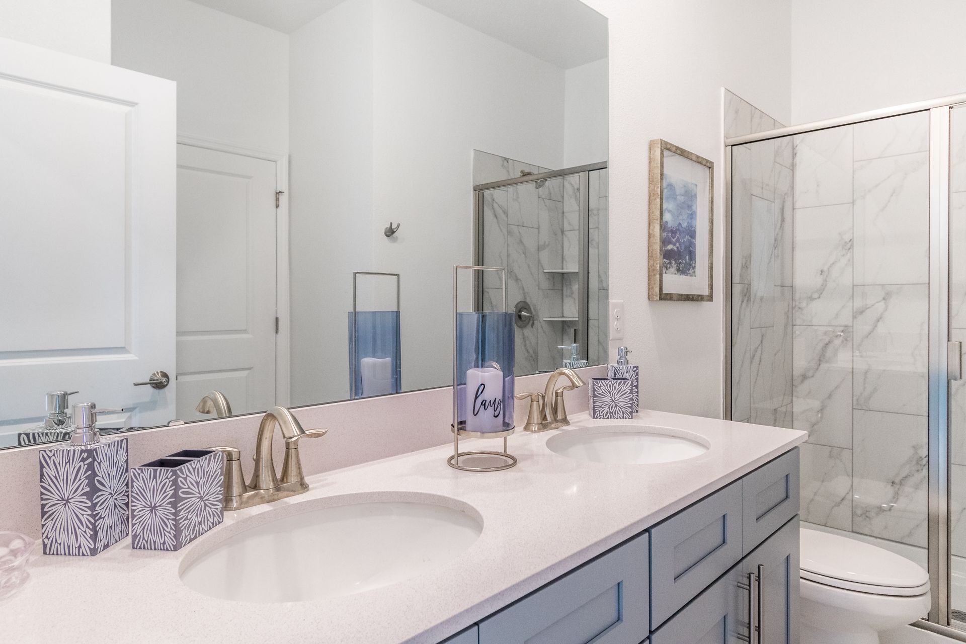Elegant bathroom with double vanity, marble shower, modern fixtures, and calming decor
