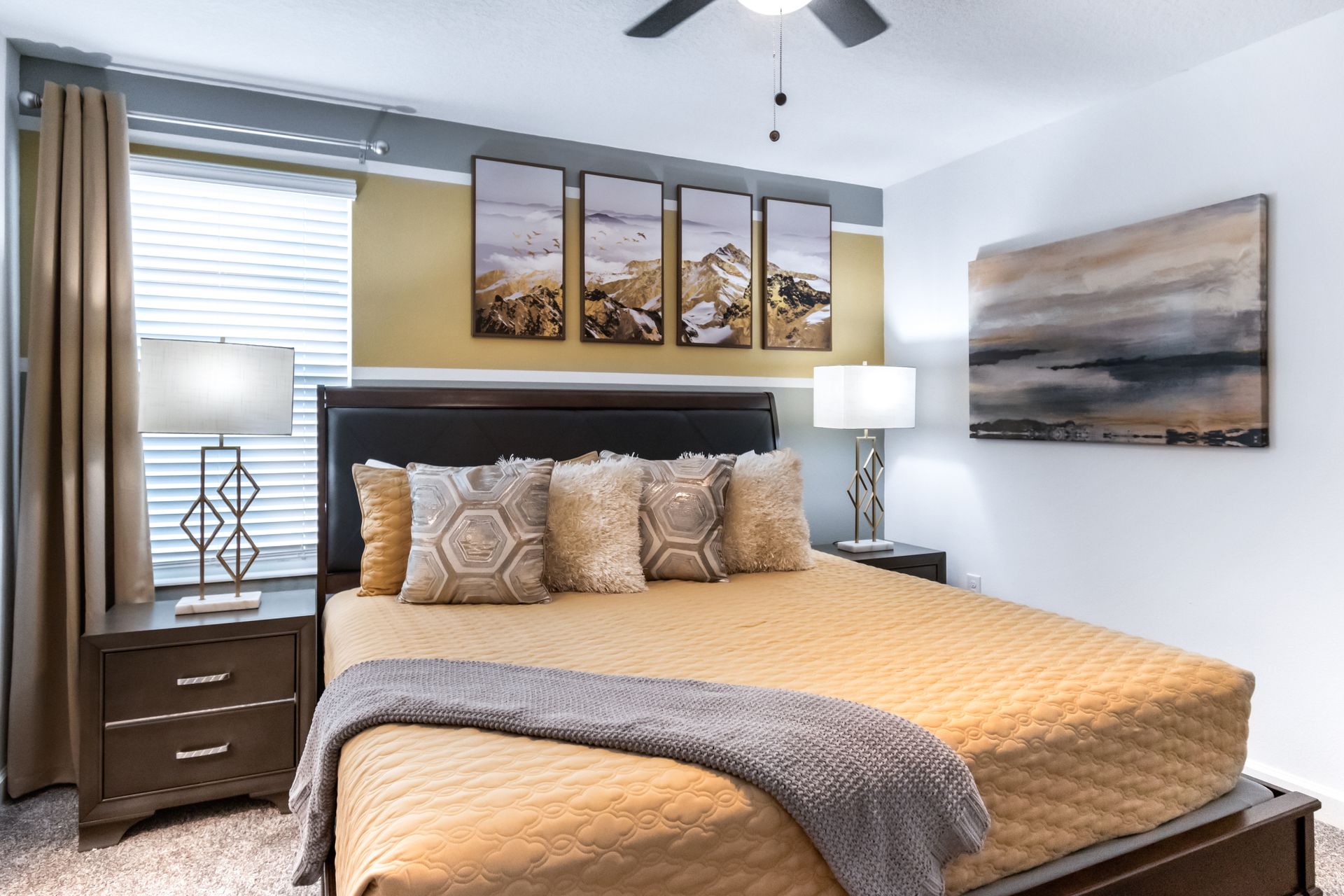 Warm and inviting bedroom with king bed, cozy bedding, modern lamps, and art
