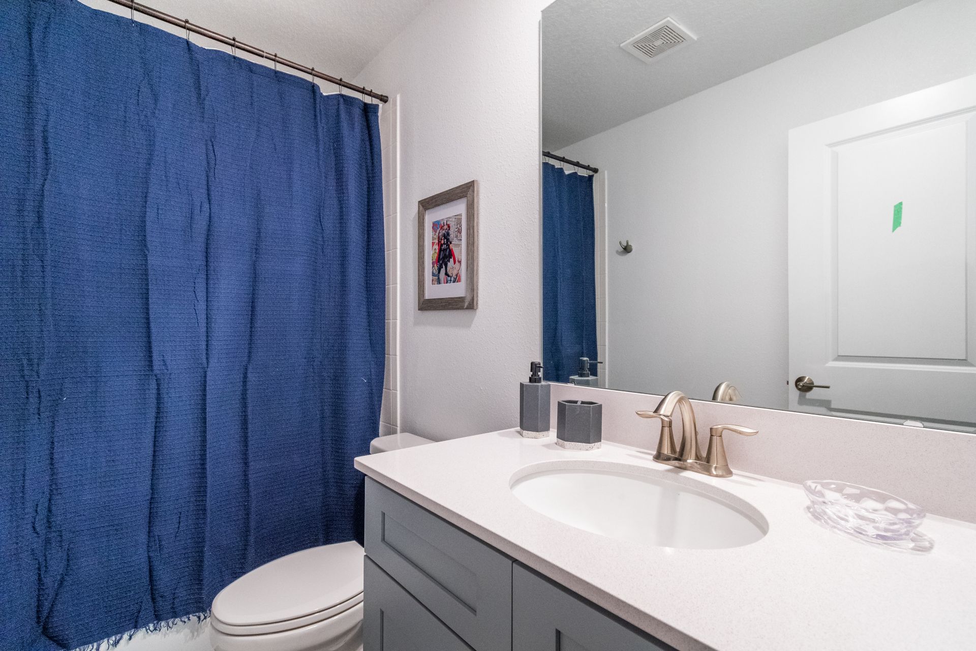 Cozy kids bathroom with superhero decor, blue shower curtain, and modern vanity
