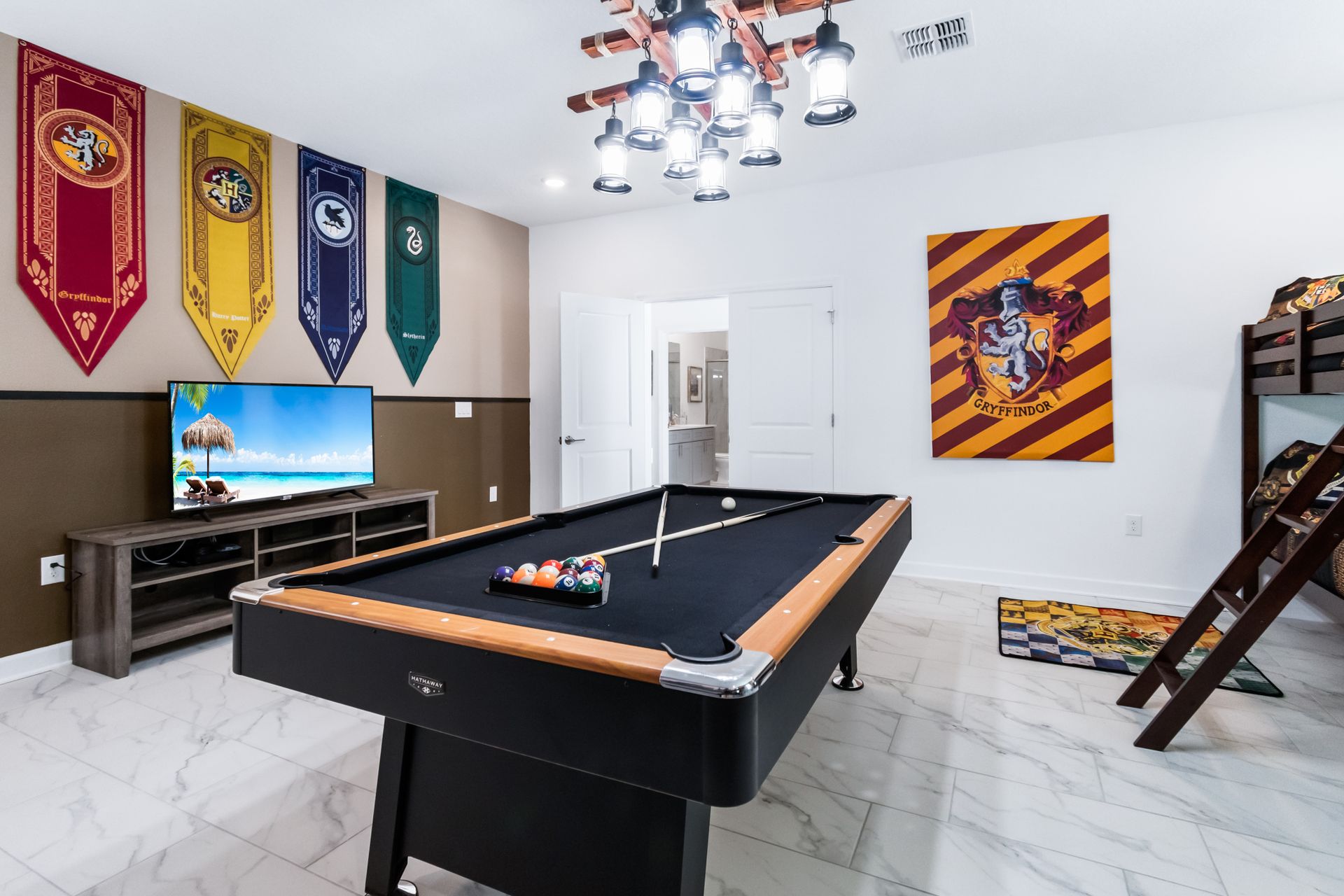 Wizard-themed game room with pool table, TV, house banners, and cozy bunk beds
