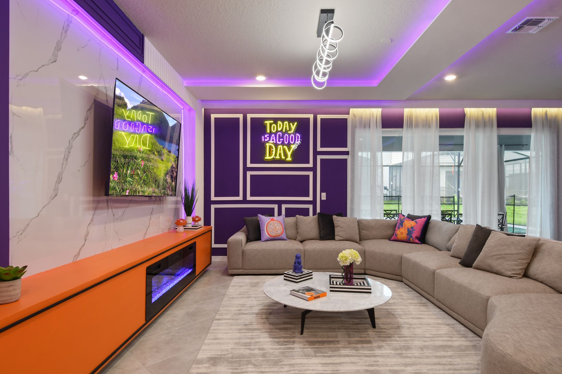 Stylish living room with neon decor, cozy sectional, and modern entertainment setup.