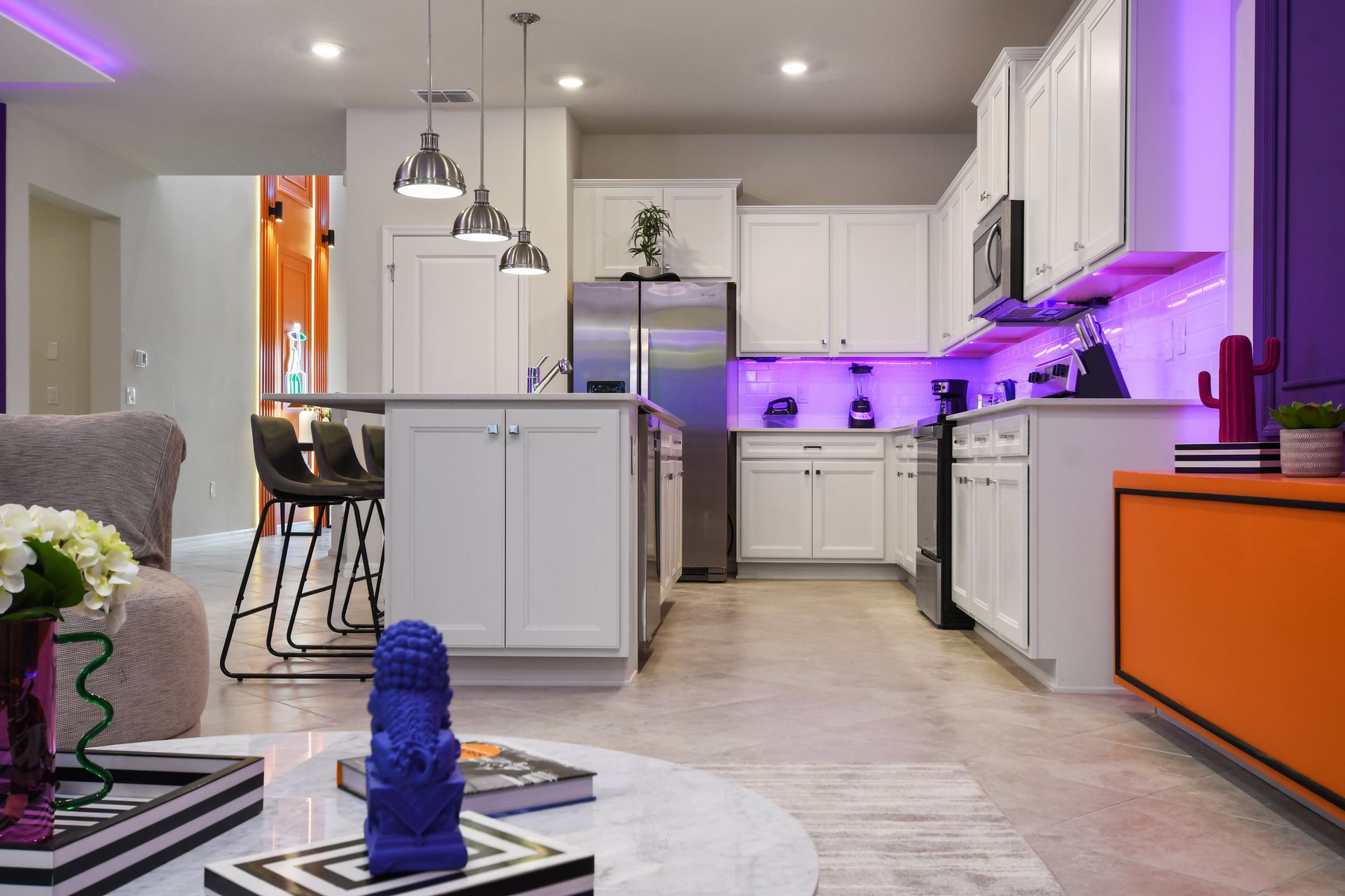 Modern kitchen with vibrant LED lighting, island seating, and stylish decor.