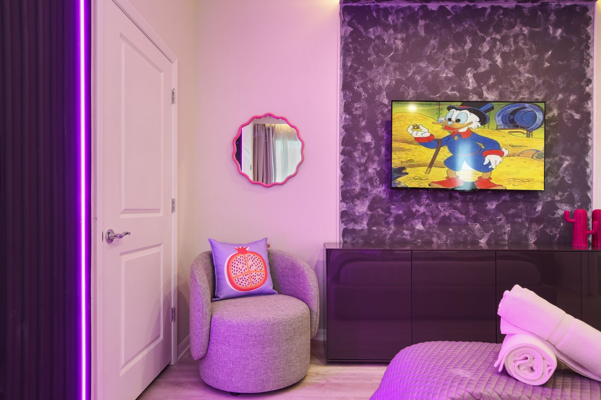 Cozy bedroom corner with plush chair, neon accents, and fun wall decor.
