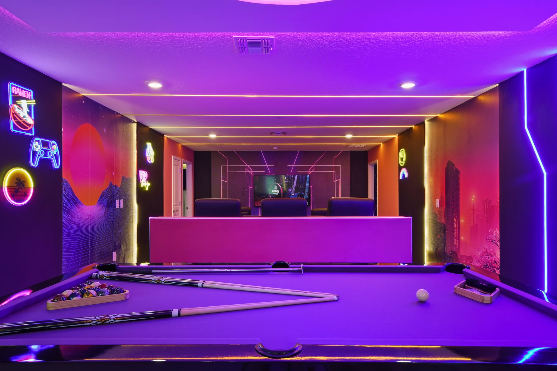 Futuristic game room with neon lights, pool table, and a home theater setup.