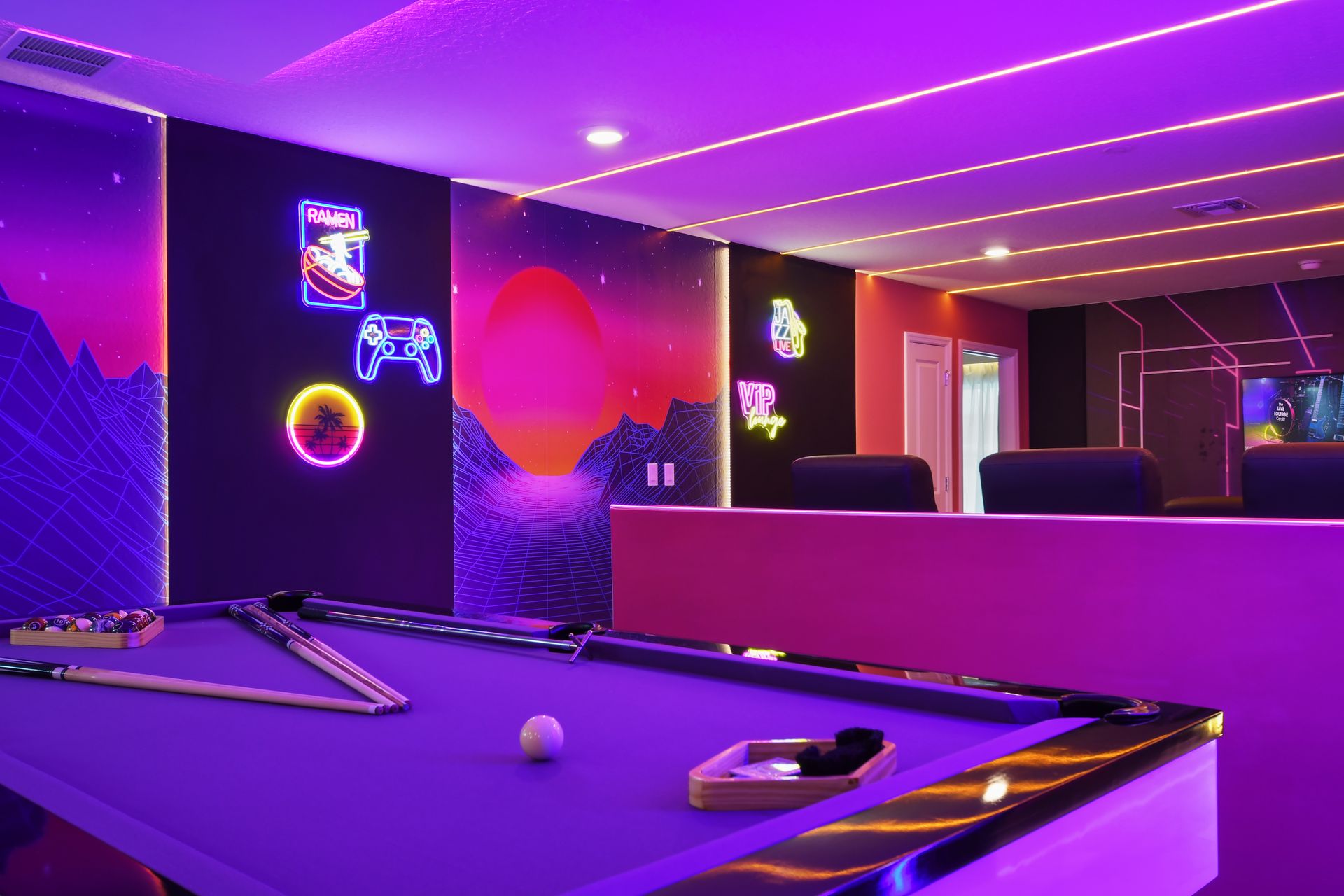 Vibrant neon-lit game room with pool table and immersive gaming setup.