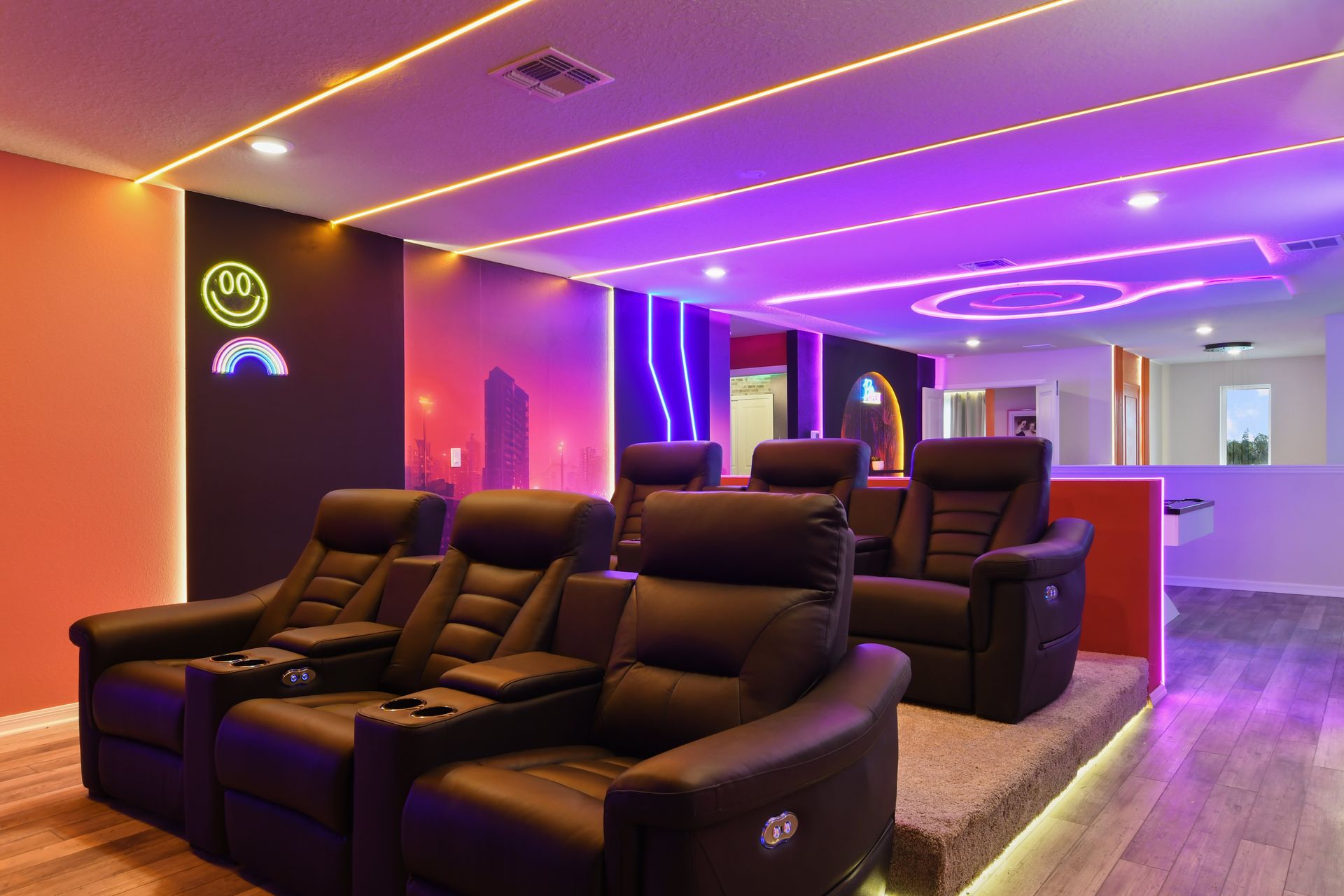 Neon-lit home theater with plush recliners, modern design, and cozy ambiance.