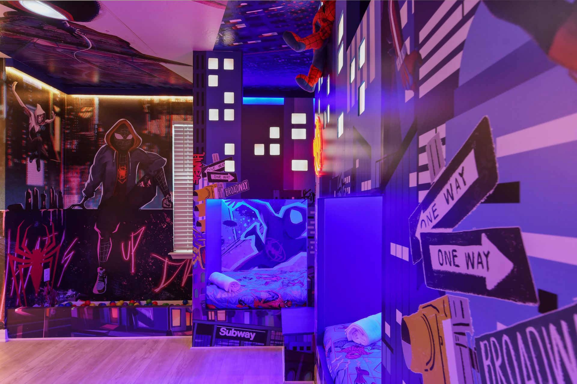 Vibrant superhero-themed room with neon lights, bunk beds, and cityscape murals.