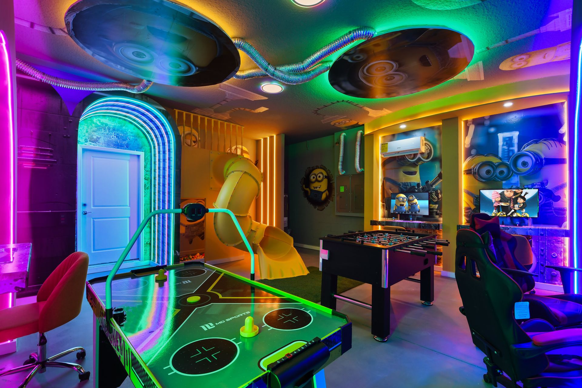Vibrant Minion-themed game room with slide, air hockey, and gaming stations.