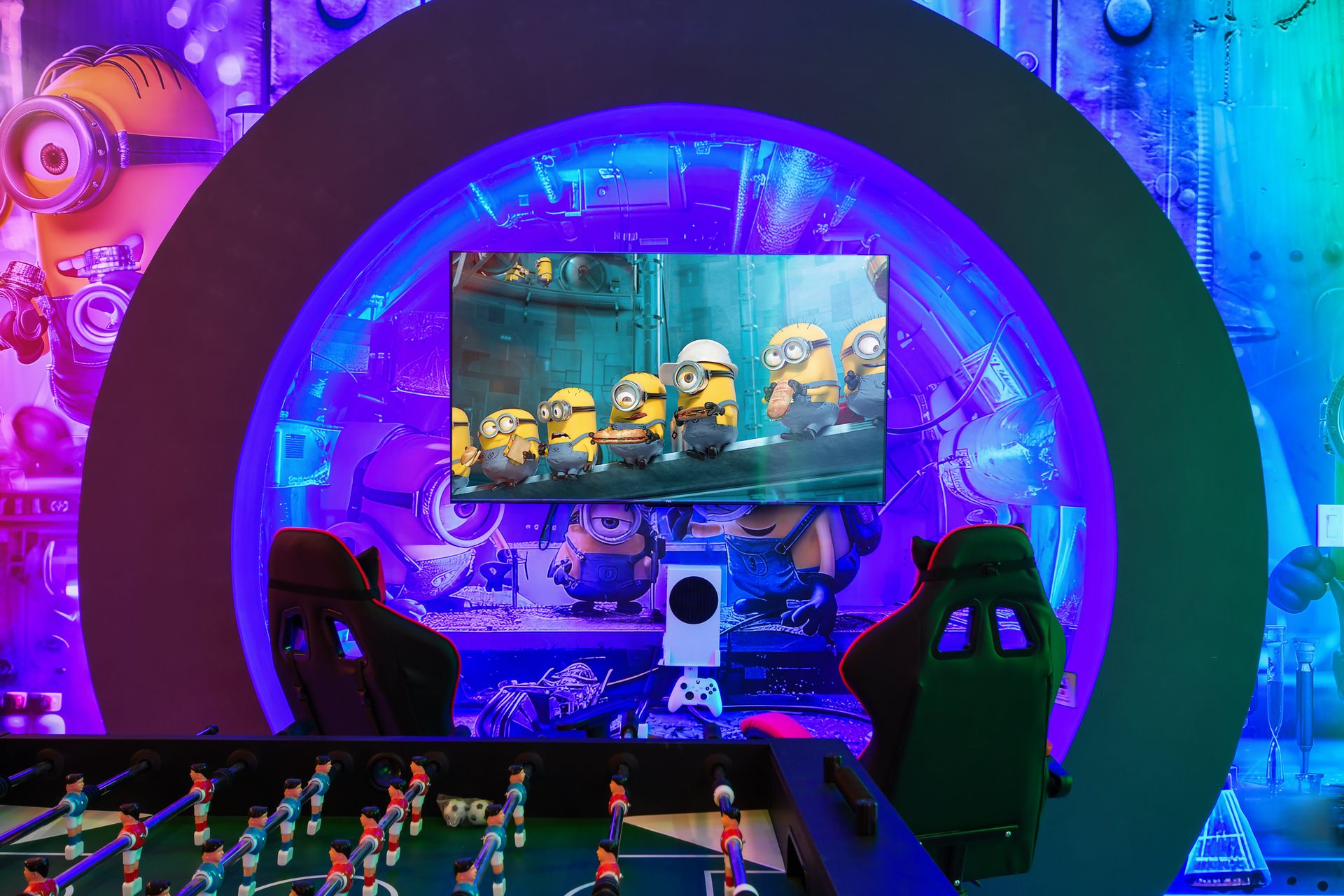Minion-themed gaming station with vibrant neon lights and foosball table.