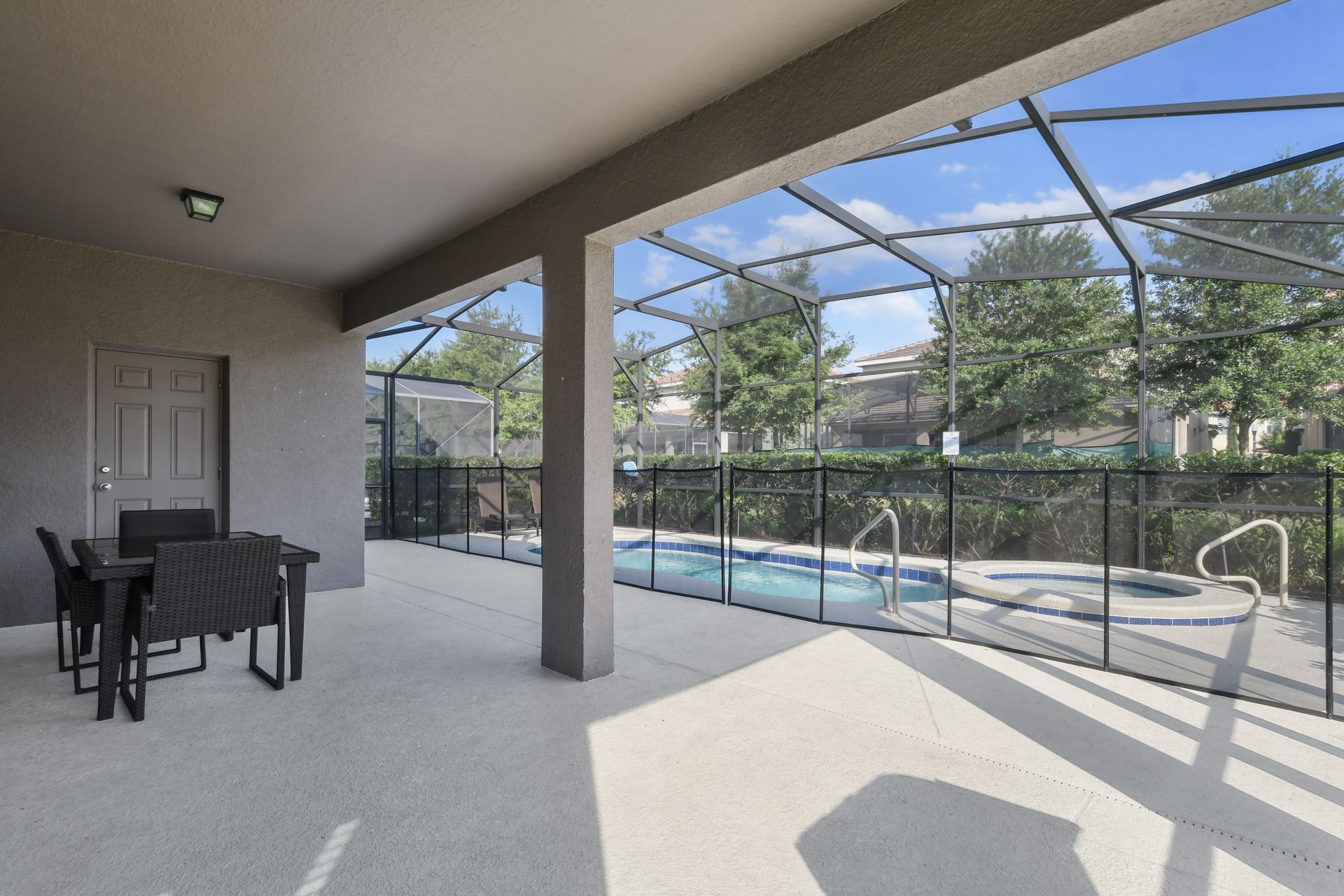 Covered patio with dining space, private spa, and screened-in pool access.