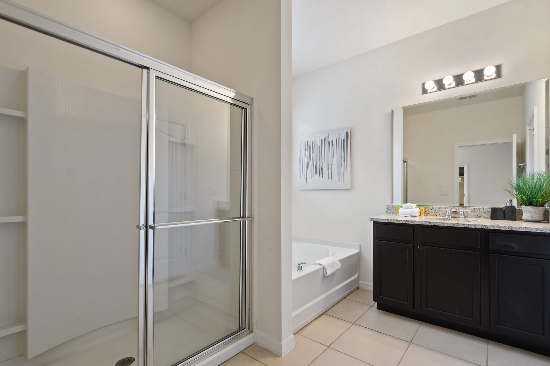 Bright ensuite with walk-in shower, soaking tub, granite countertops, and storage.