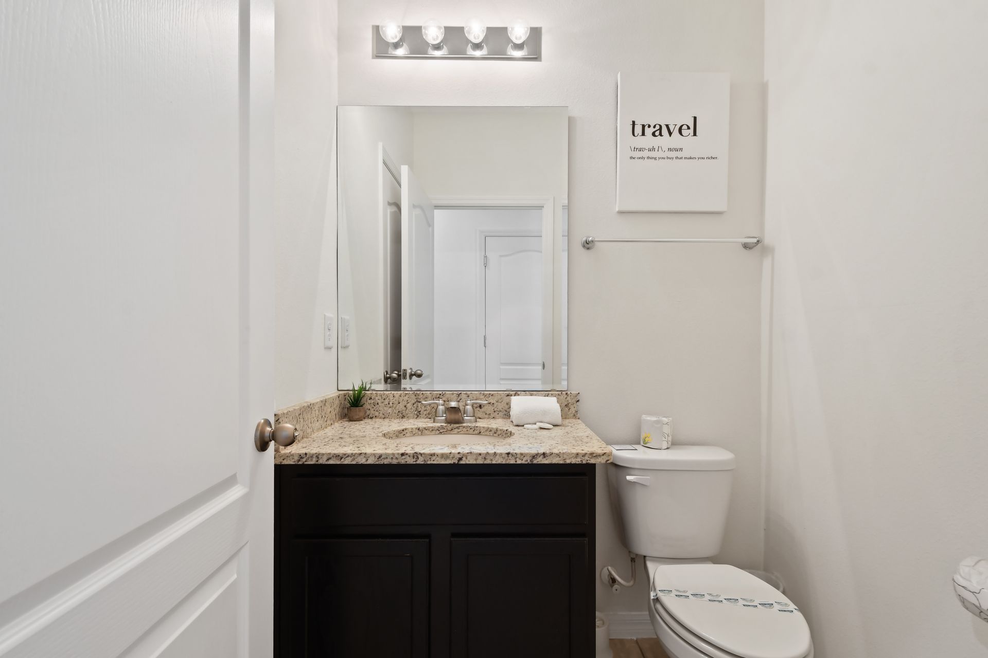 Chic half-bath with granite countertop and modern decor, perfect for guests.