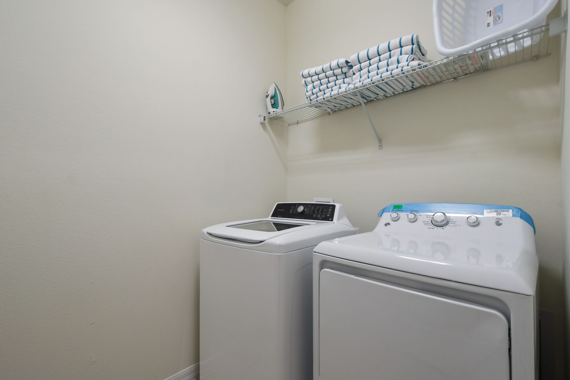 Full laundry room with washer, dryer, ironing board, and fresh folded towels.