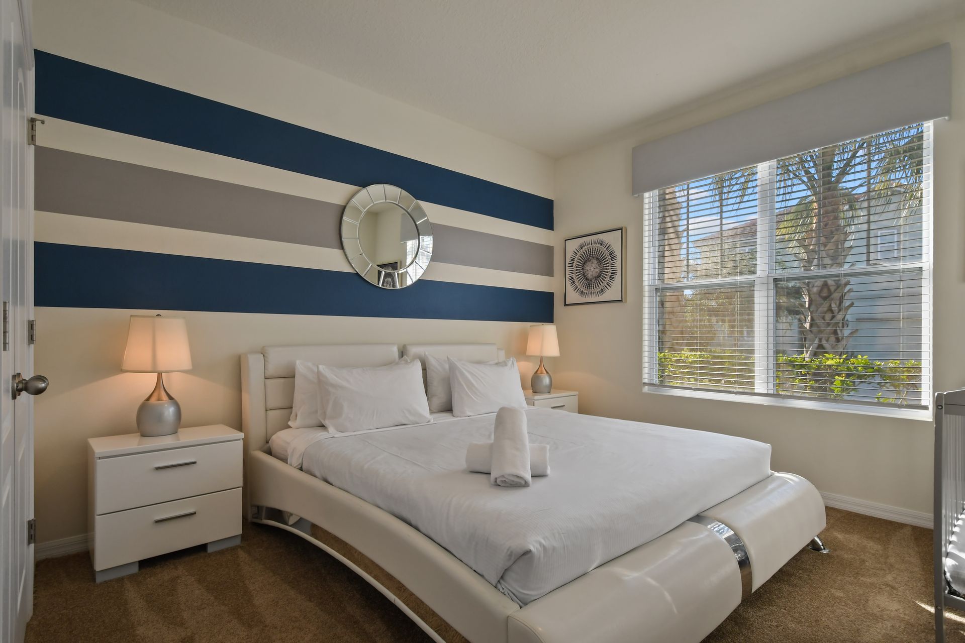 Modern queen bedroom with bold striped accent wall and plenty of natural light.