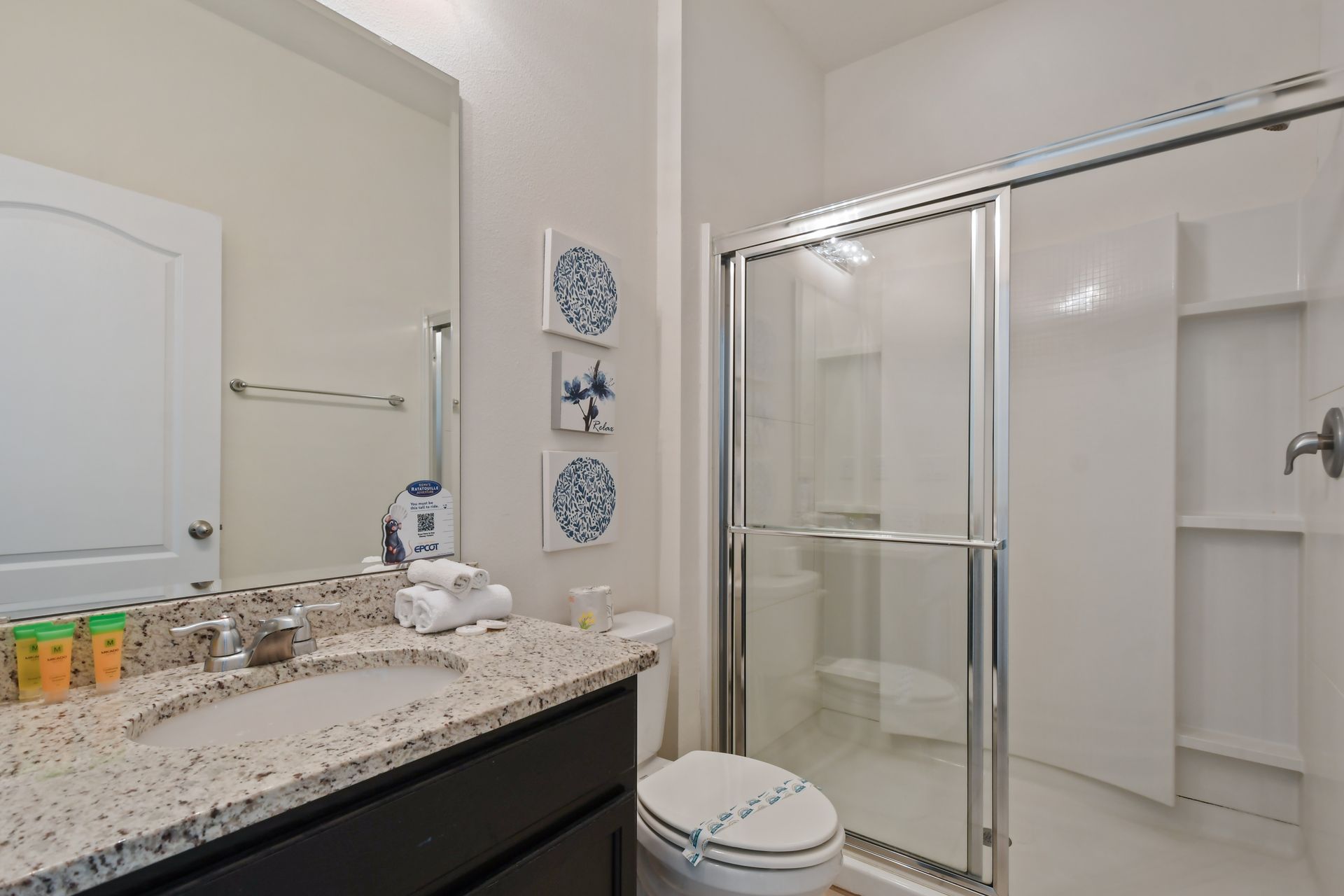 Bright and modern bathroom with granite vanity and a spacious walk-in shower.