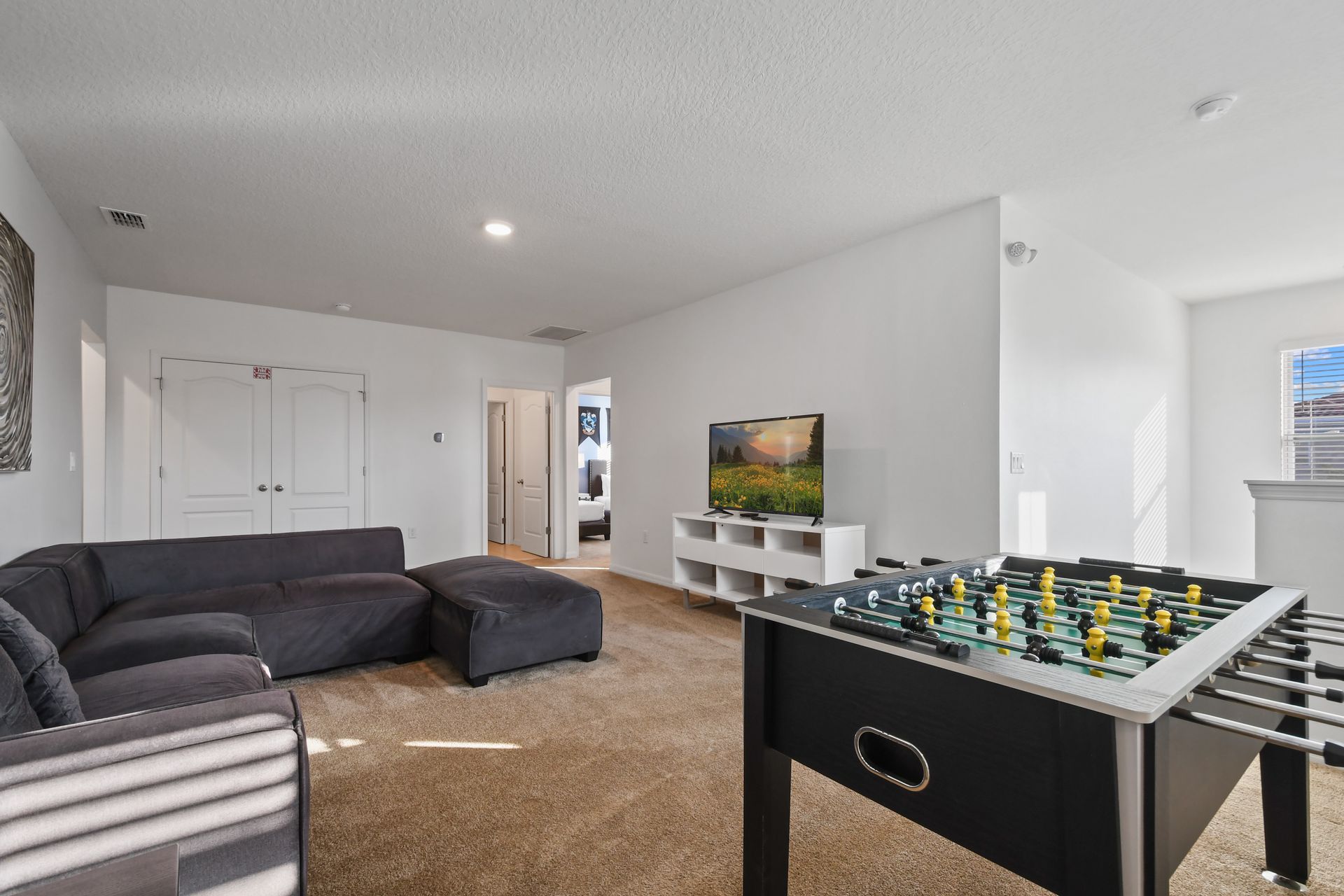 Spacious upstairs loft with foosball, cozy sectional, and a large smart TV for fun.