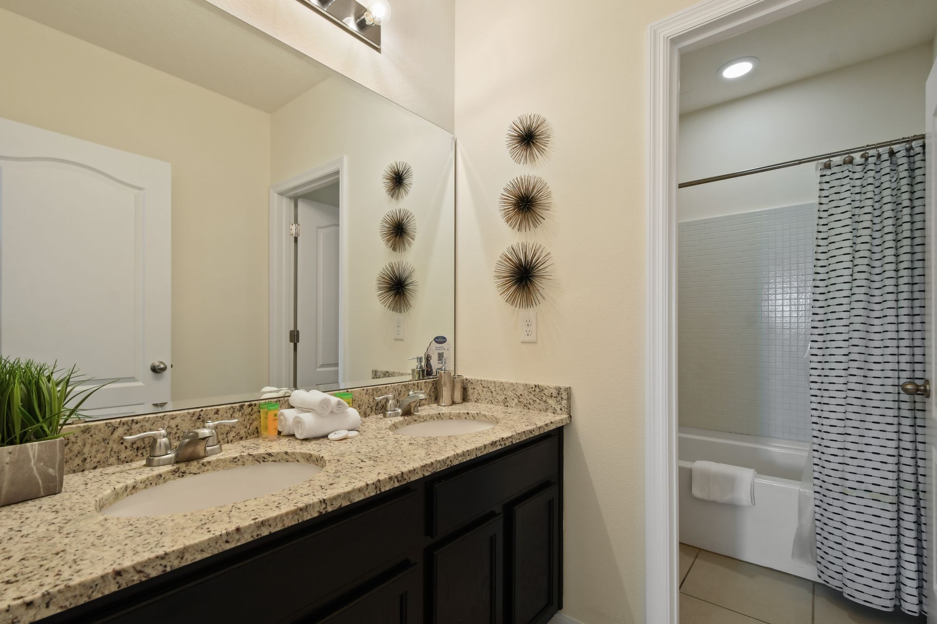 Stylish bathroom with double vanity, granite counters, and tub-shower combo.