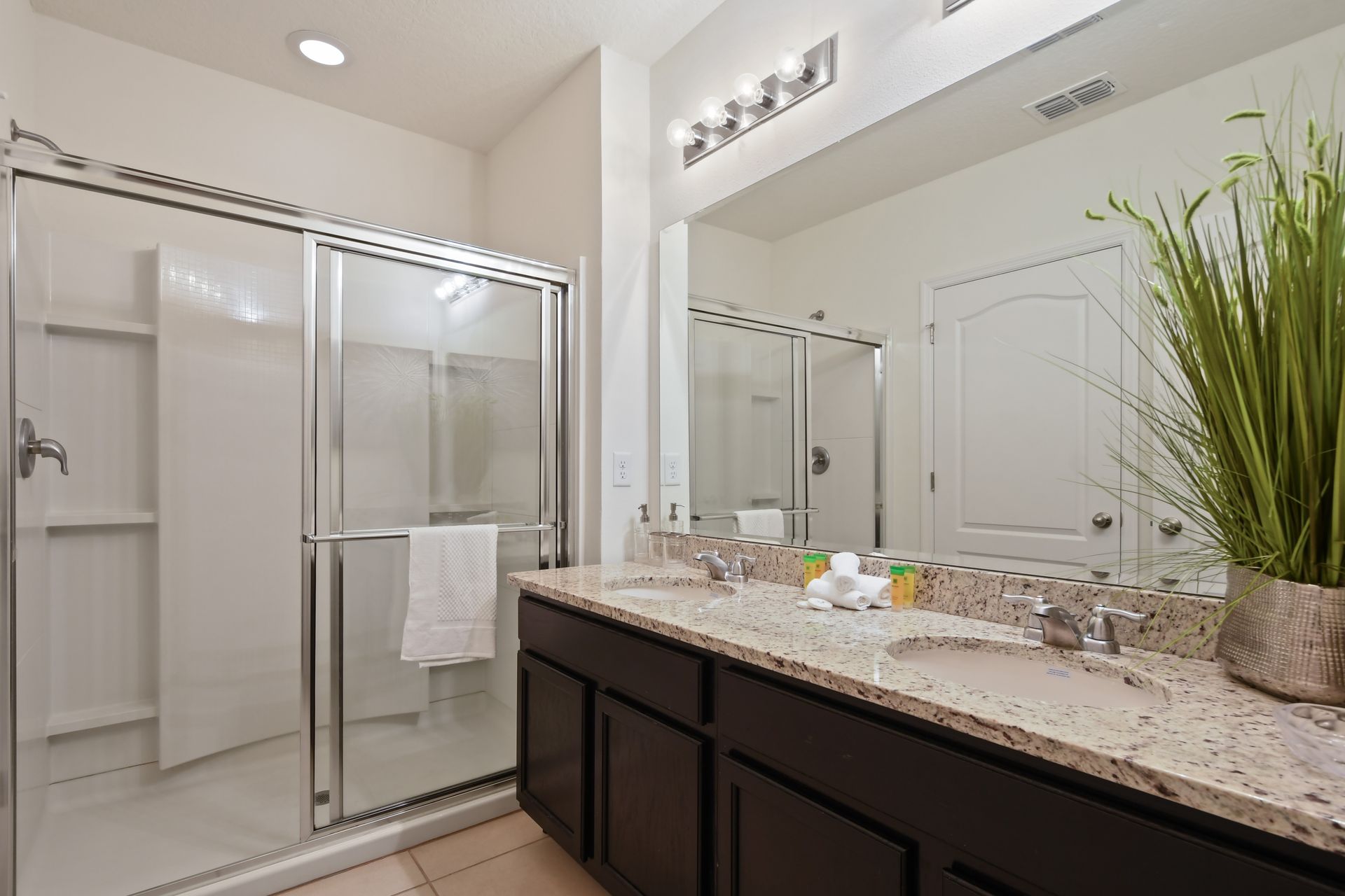 Spacious double vanity with granite countertops and a sleek glass walk-in shower.