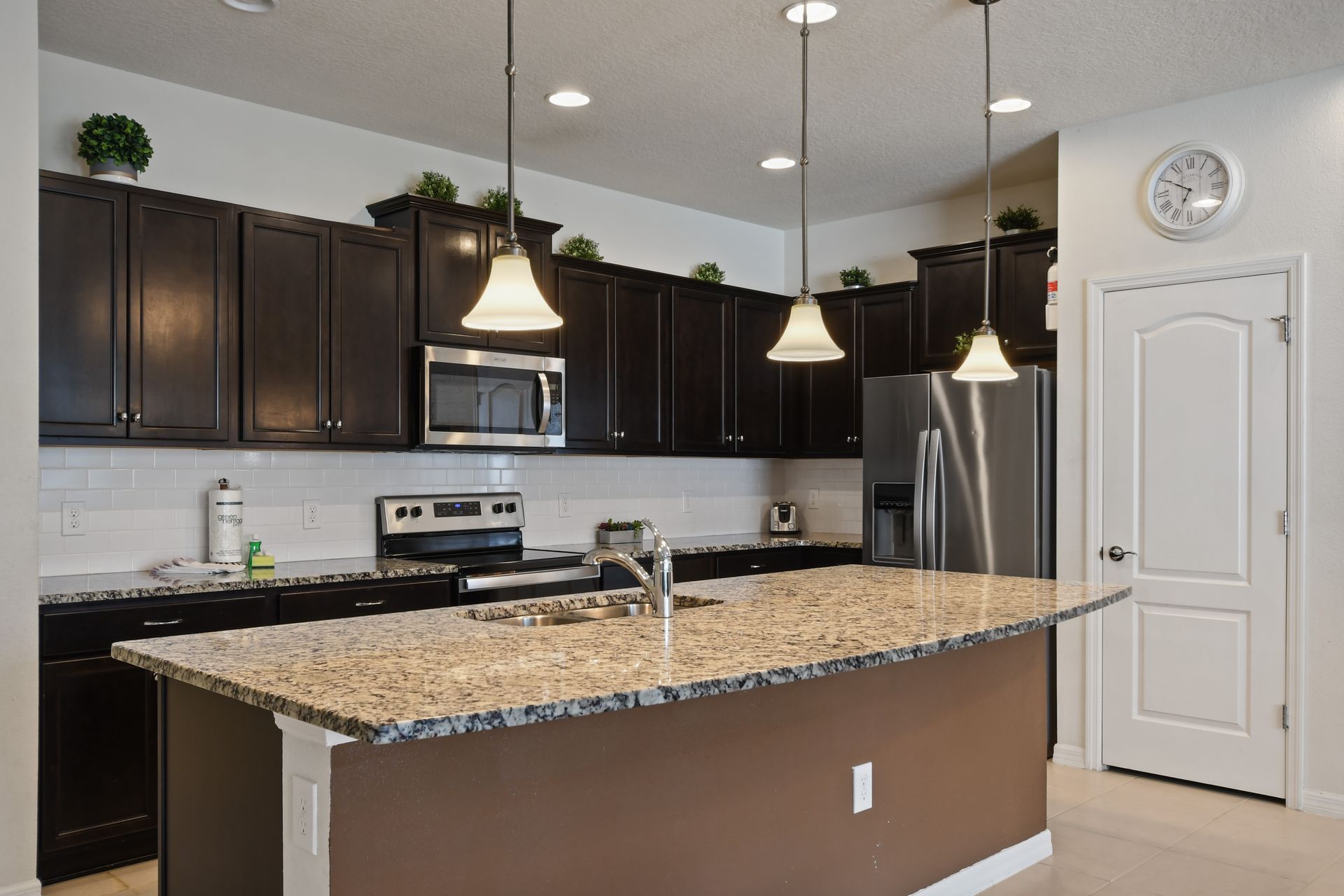Spacious kitchen with granite island, dark wood cabinetry, and stainless appliances.