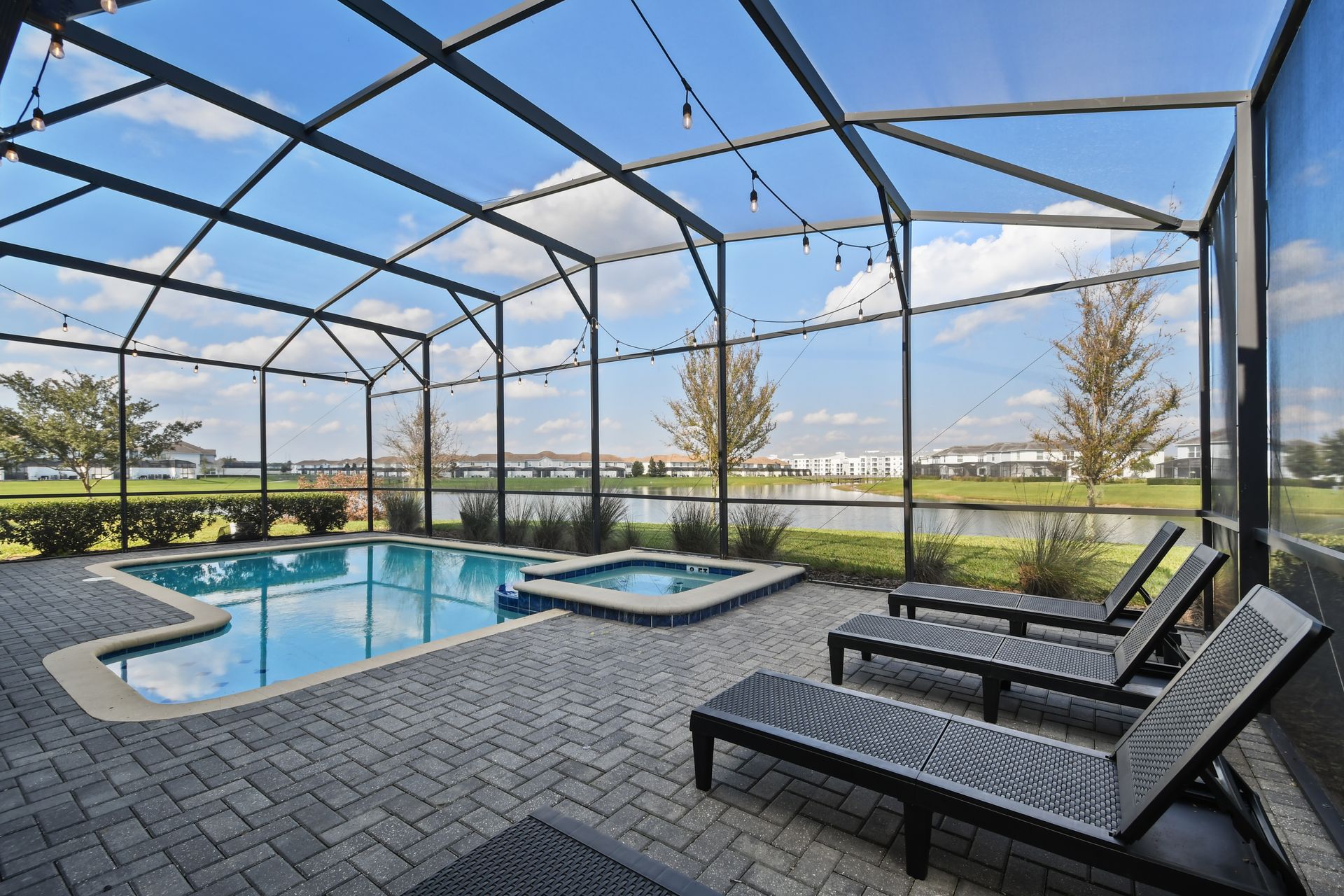 Lounge lakeside in this screened pool and spa oasis with sunny views and string lights!