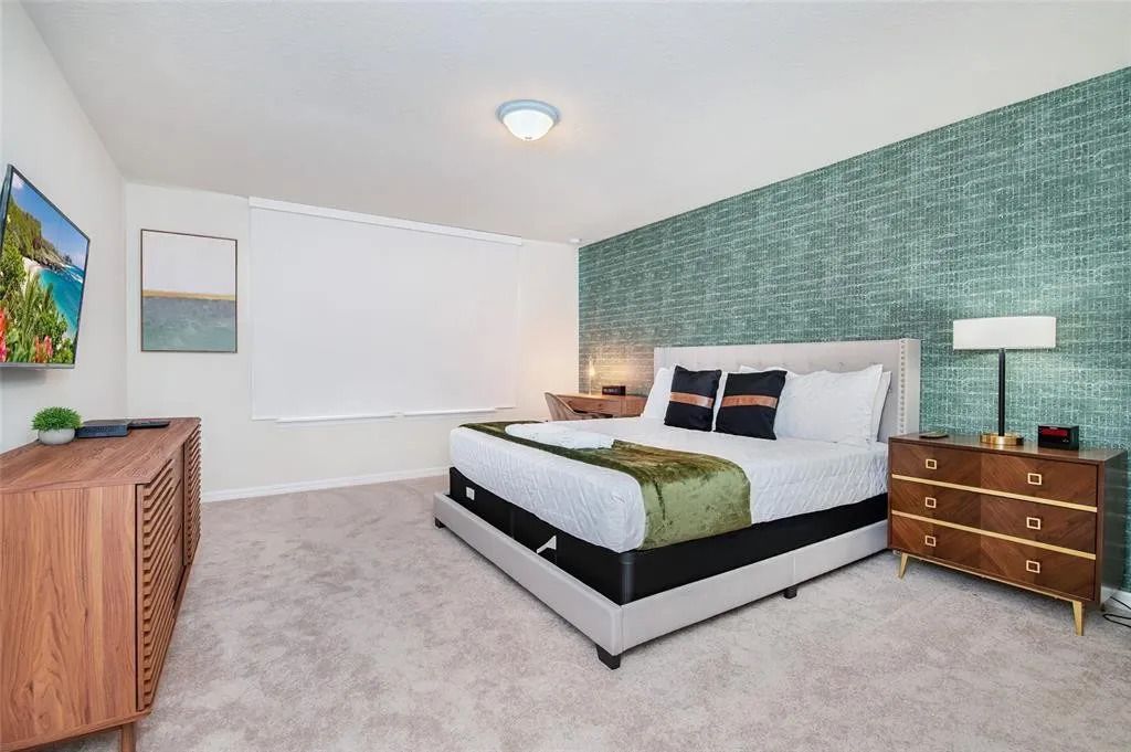 Spacious primary suite with king bed, bold accent wall, and modern furnishings.