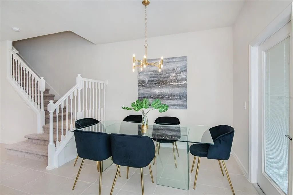 Elegant dining area with glass table, velvet chairs, and modern chandelier.