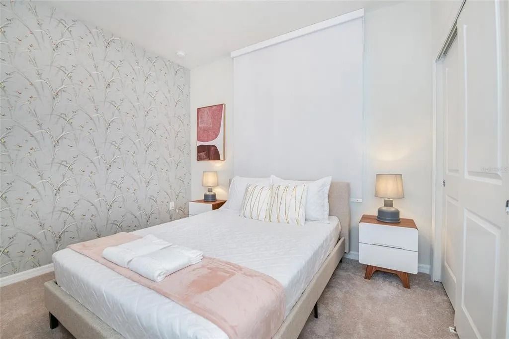 Serene bedroom with soft tones, cozy bedding, and elegant botanical wallpaper.