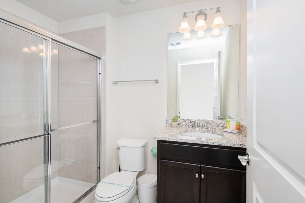 Bright bathroom with granite double vanity, full tub, and cheerful decor touches.