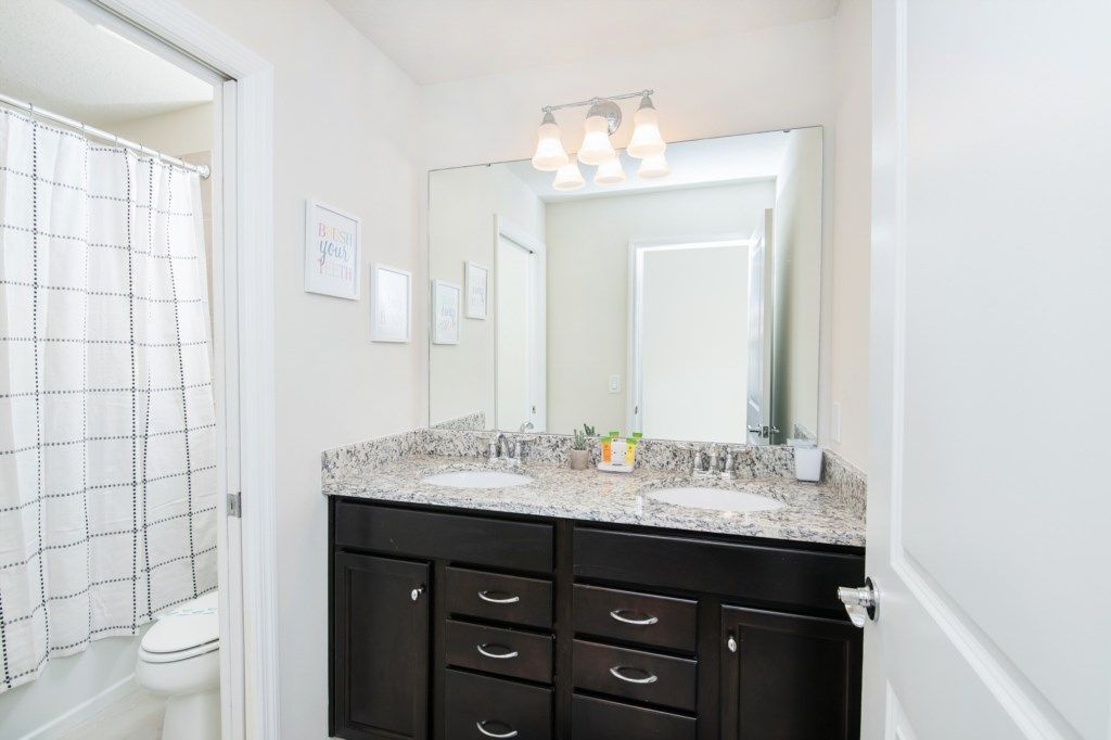 Bright bathroom with granite double vanity, full tub, and cheerful decor touches.