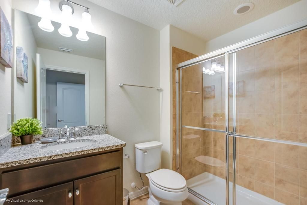Elegant full bathroom with granite counters and a modern walk-in shower.