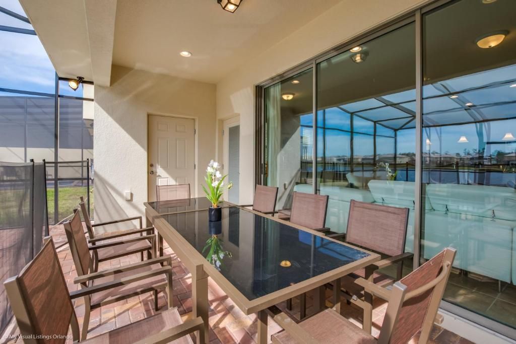 Spacious covered patio with glass dining table, pool views, and outdoor comfort.