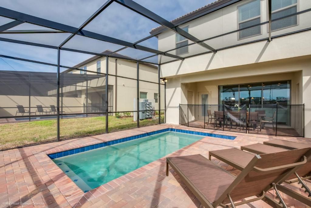 Relaxing screened pool area with sun loungers, outdoor dining, and privacy fence.