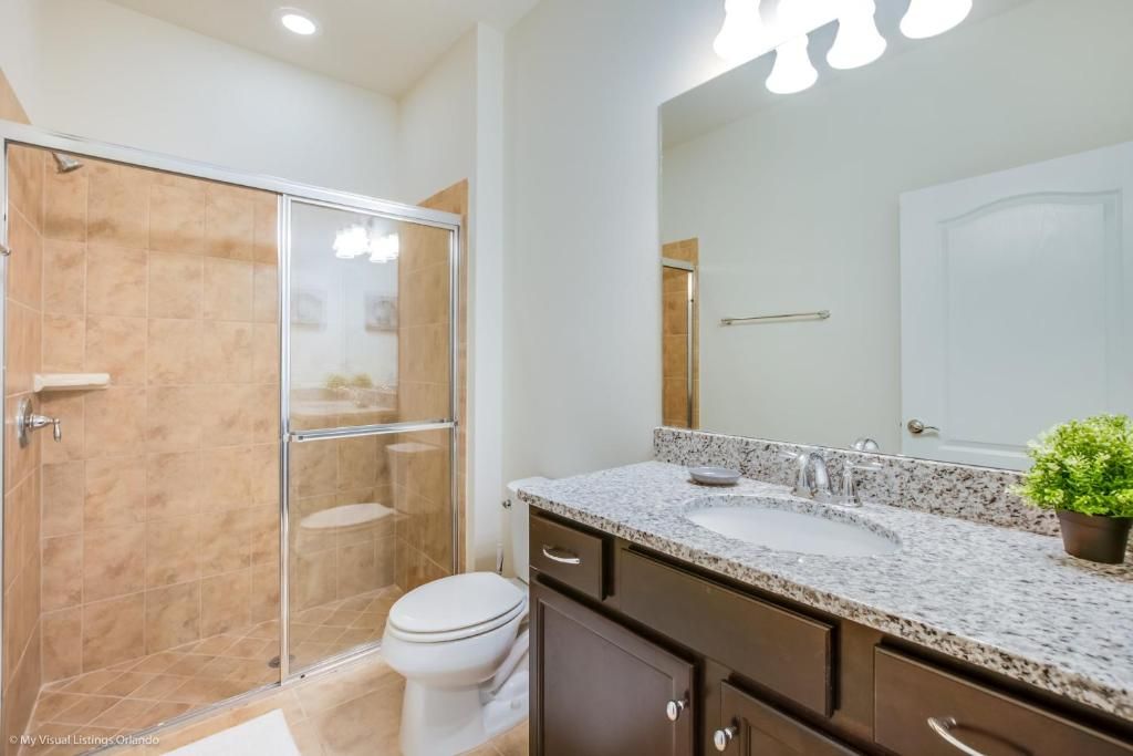 Bright modern bathroom with granite vanity and a sleek glass shower.