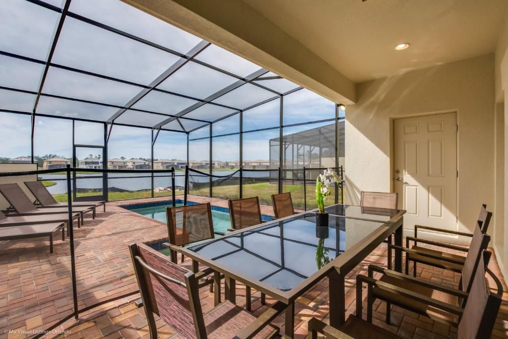 Covered patio with lake-view dining, screened pool, and relaxing outdoor seating.