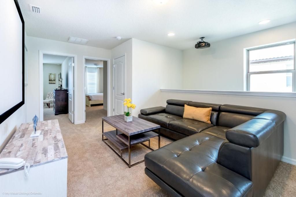 Cozy home theater loft with large sectional, projector screen, and relaxed vibe.