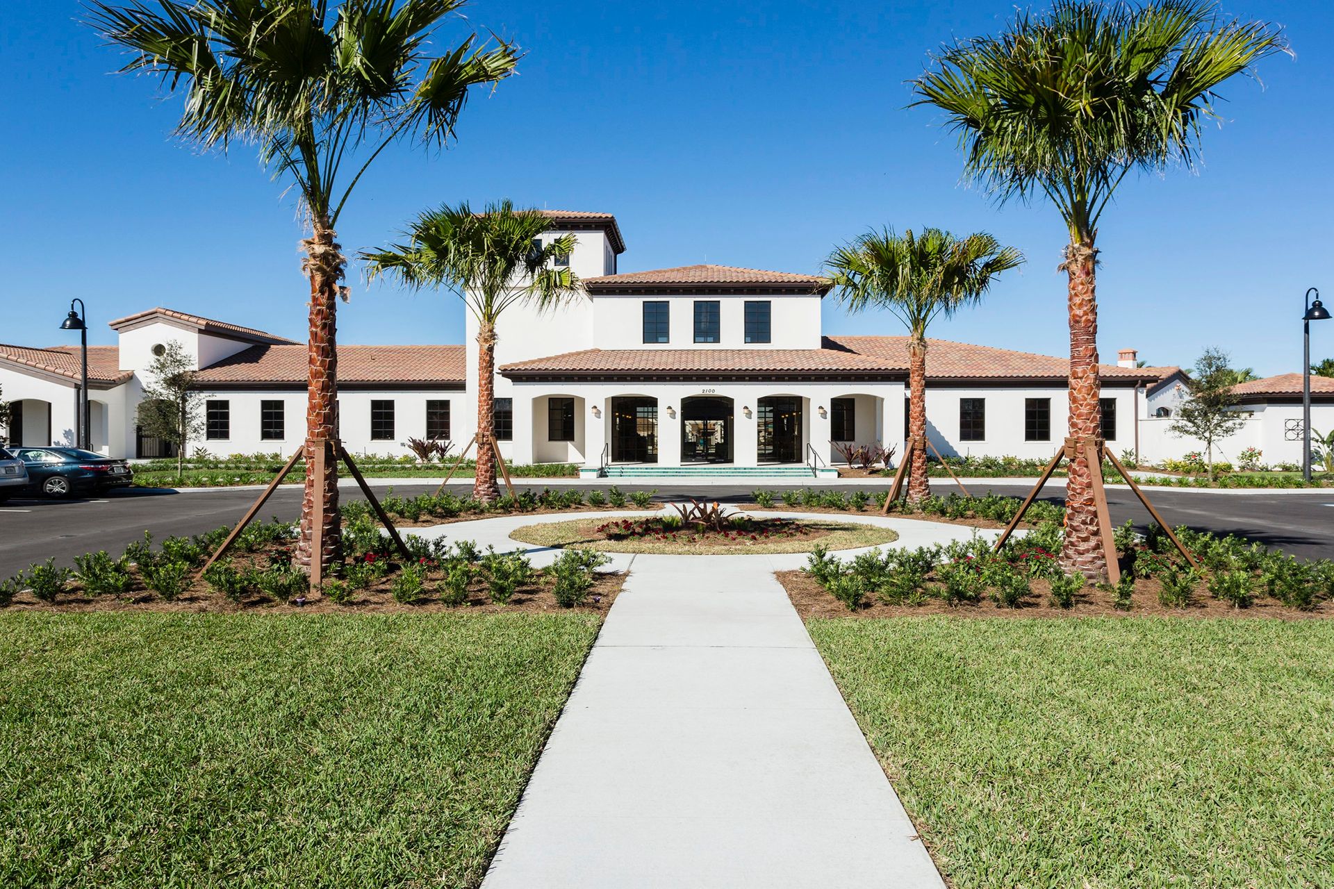 Elegant clubhouse with palm-lined entry and beautiful landscaping