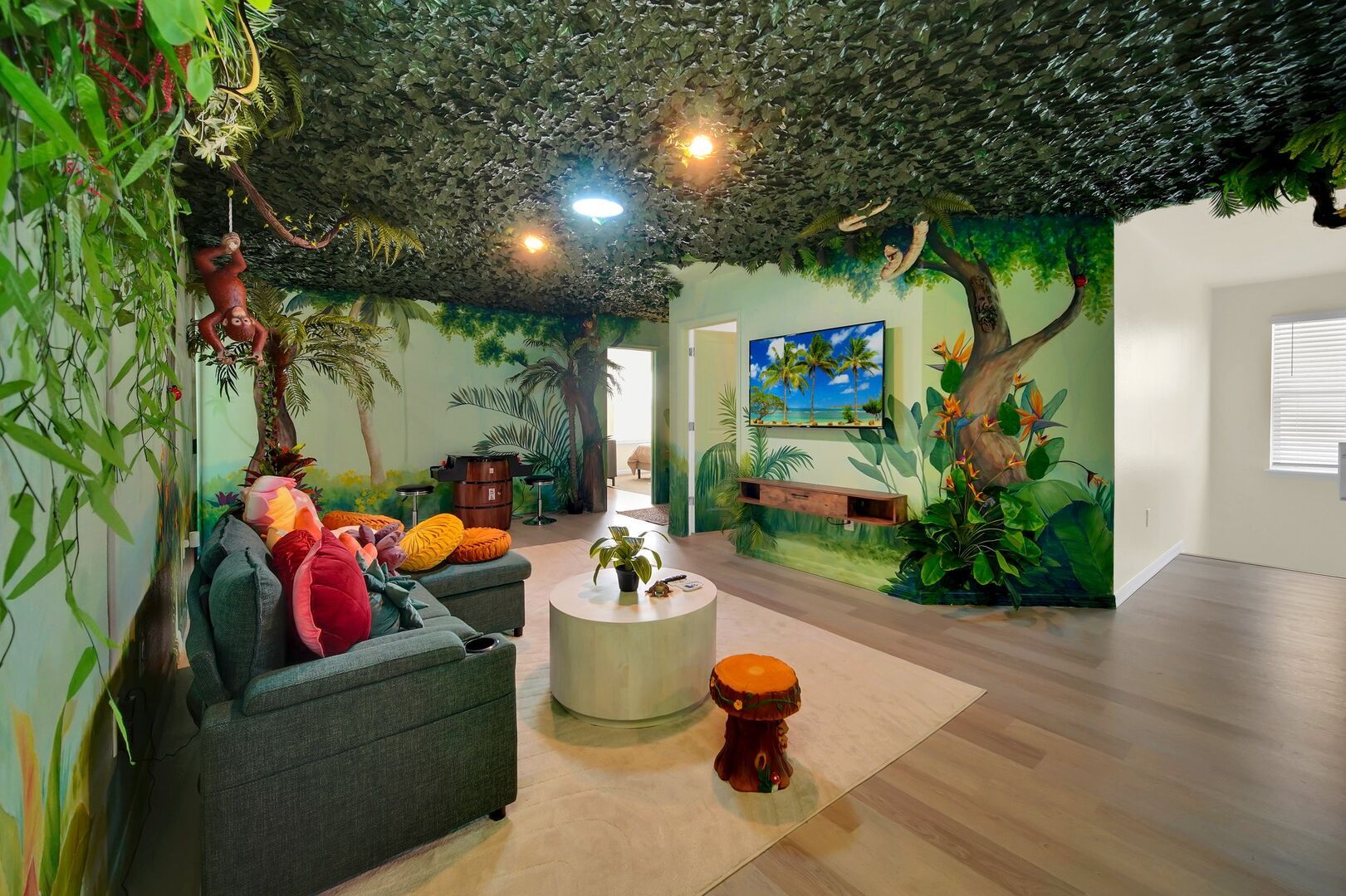 Jungle-themed lounge with vibrant decor, cozy seating, and wall-mounted TV.