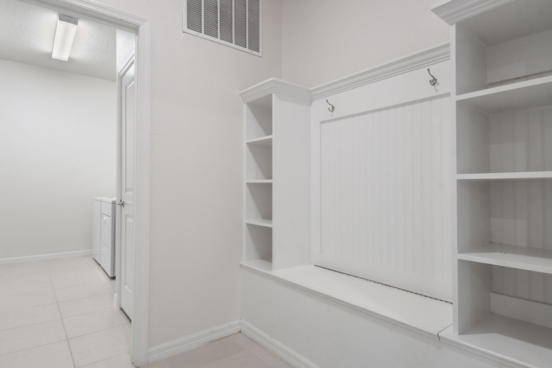 Bright mudroom with built-in shelves and hooks for storage.