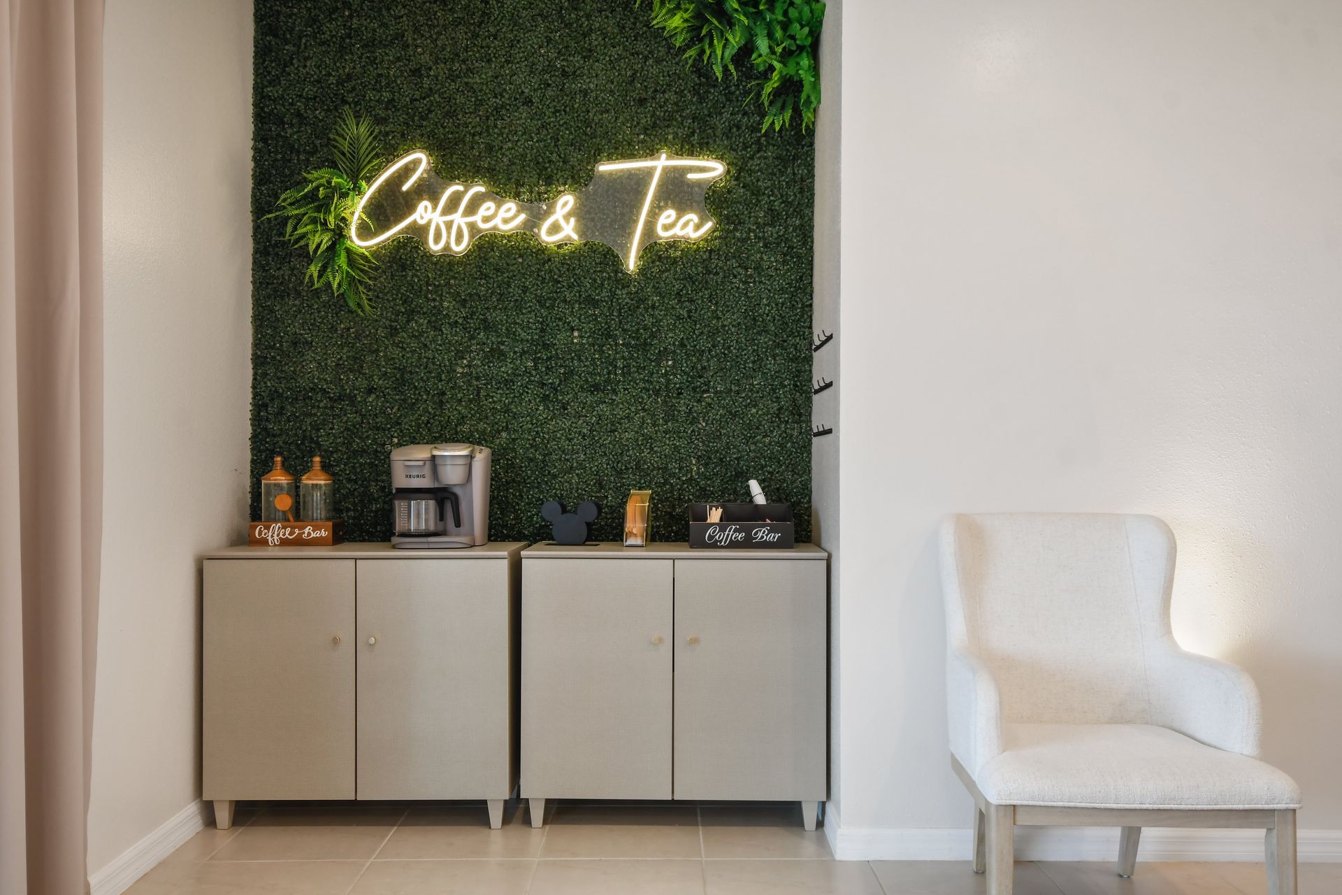Charming coffee & tea station with neon glow, lush greenery, and cozy seating!