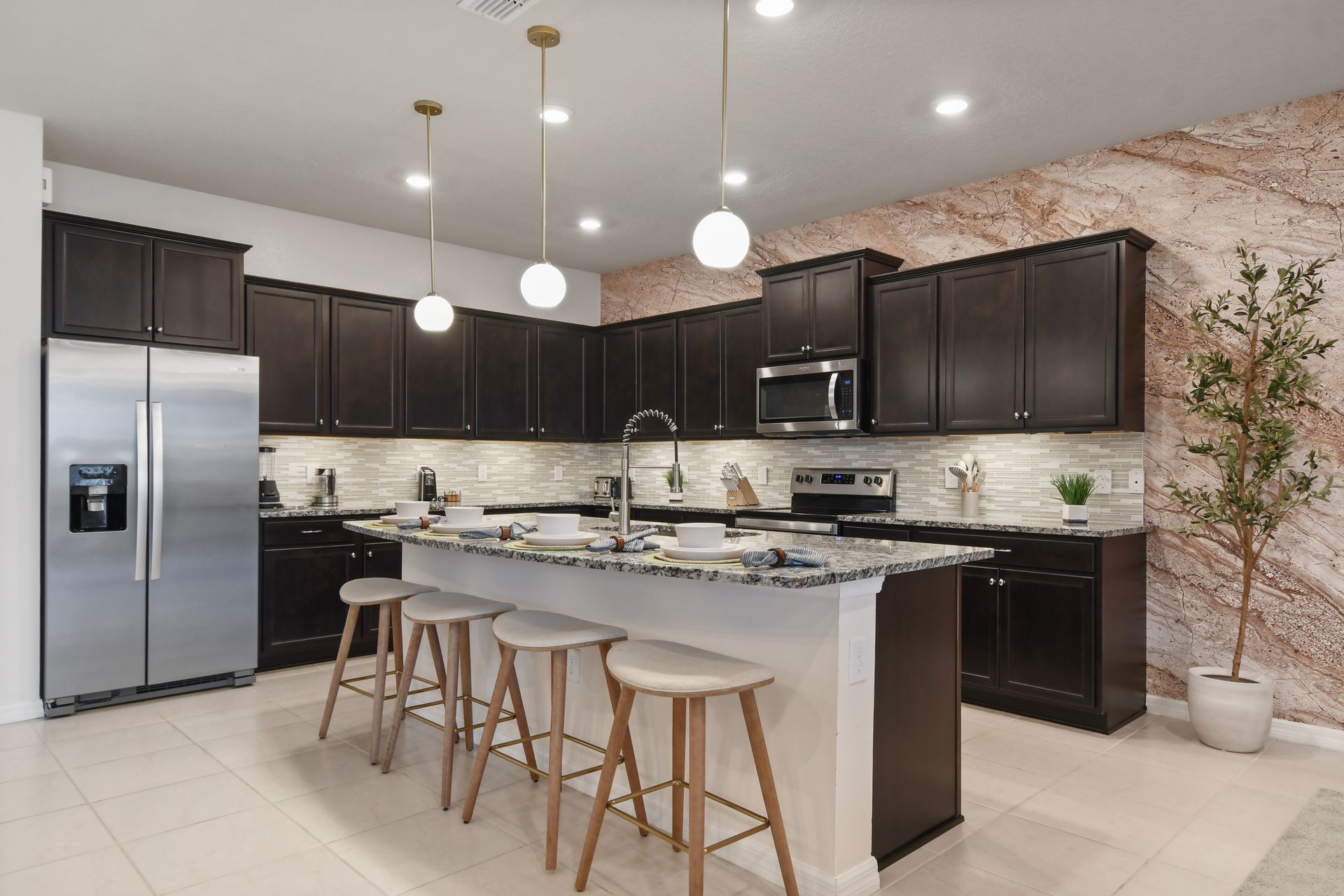 Modern kitchen with dark cabinets, granite countertops, chic lighting, and seating!
