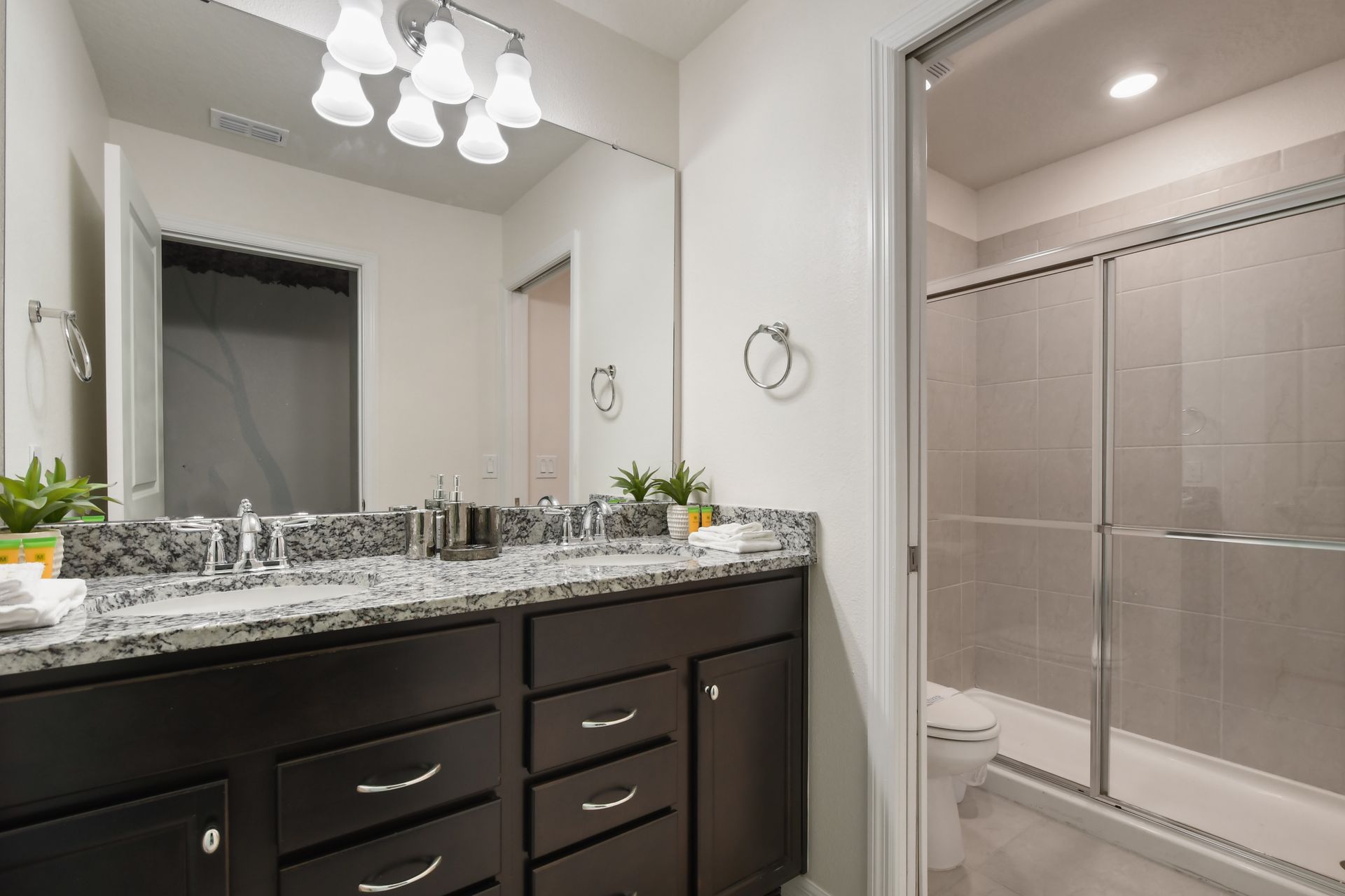 This bathroom offers a modern touch with its granite countertop, sleek dark cabinetry, and a spacious walk-in shower.