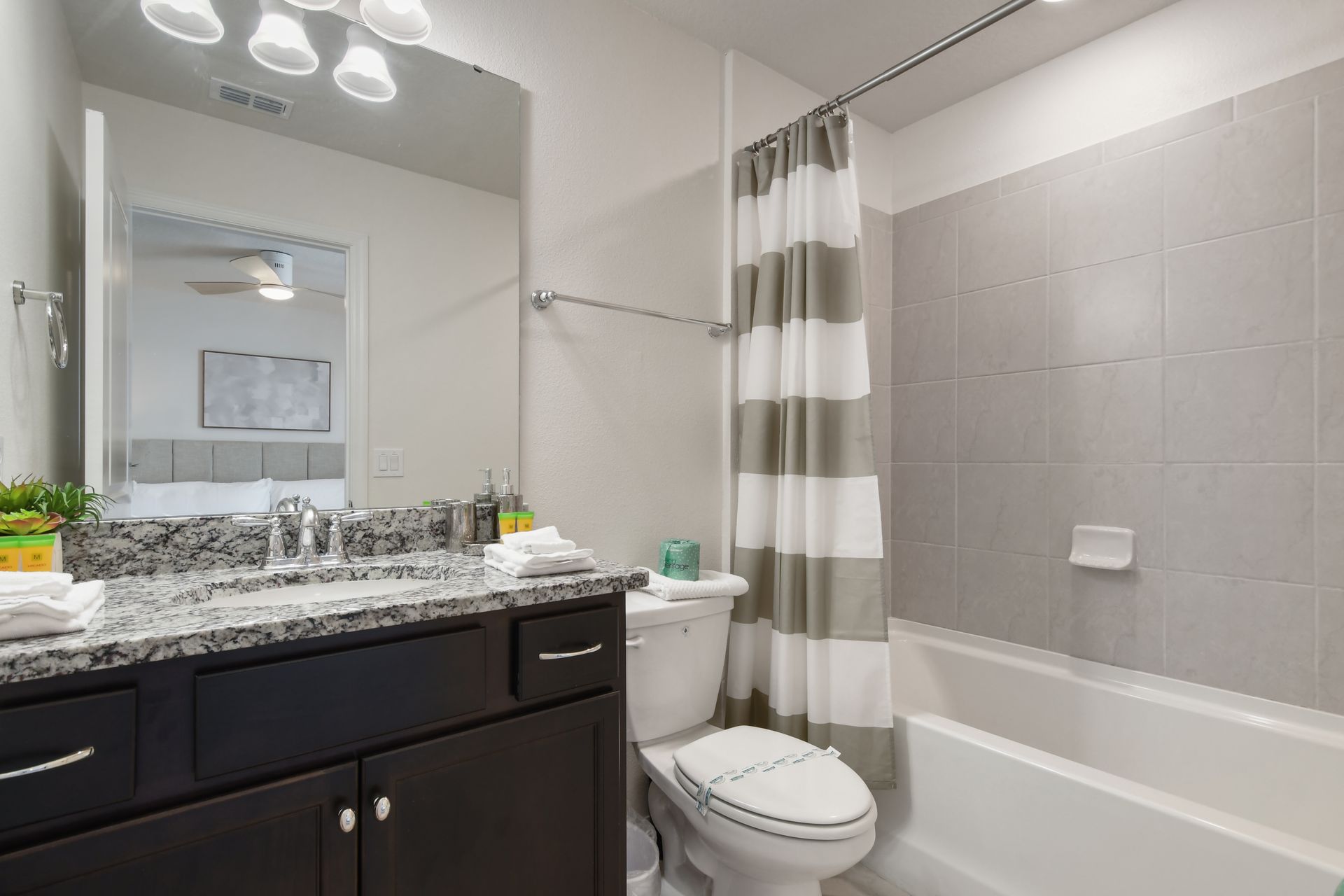 Modern bathroom with granite vanity and shower/tub combo.