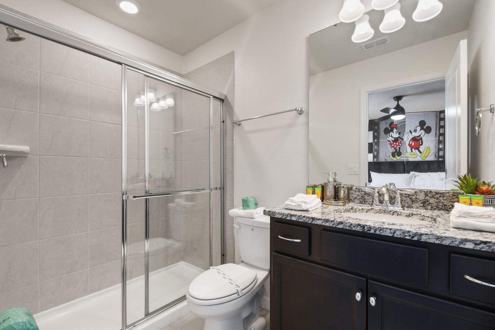 Modern bathroom with granite vanity, glass shower, and decor.