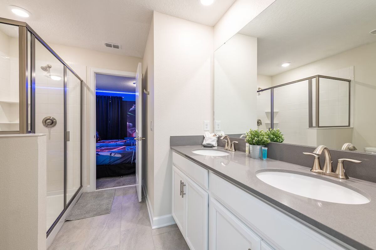 Spacious bathroom with double vanity, glass shower, and direct access to bedroom.