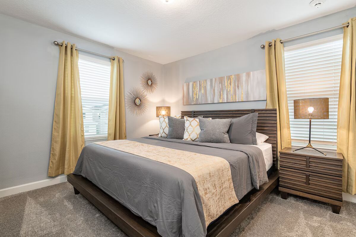 Stylish king bedroom with warm gold accents, modern art, and cozy ambiance!